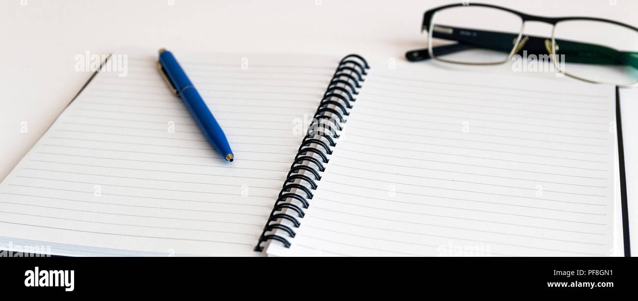 Notebook and glasses and red pen on table. White background Stock Photo