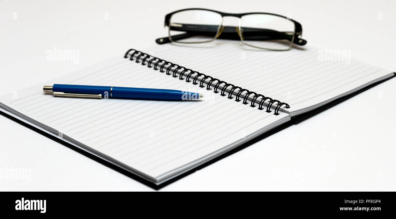 Notebook and glasses and red pen on table. White background Stock Photo