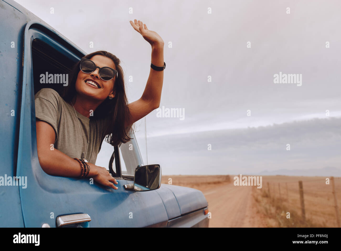 Happy woman enjoying road trip. Female traveling by a car looking out ...
