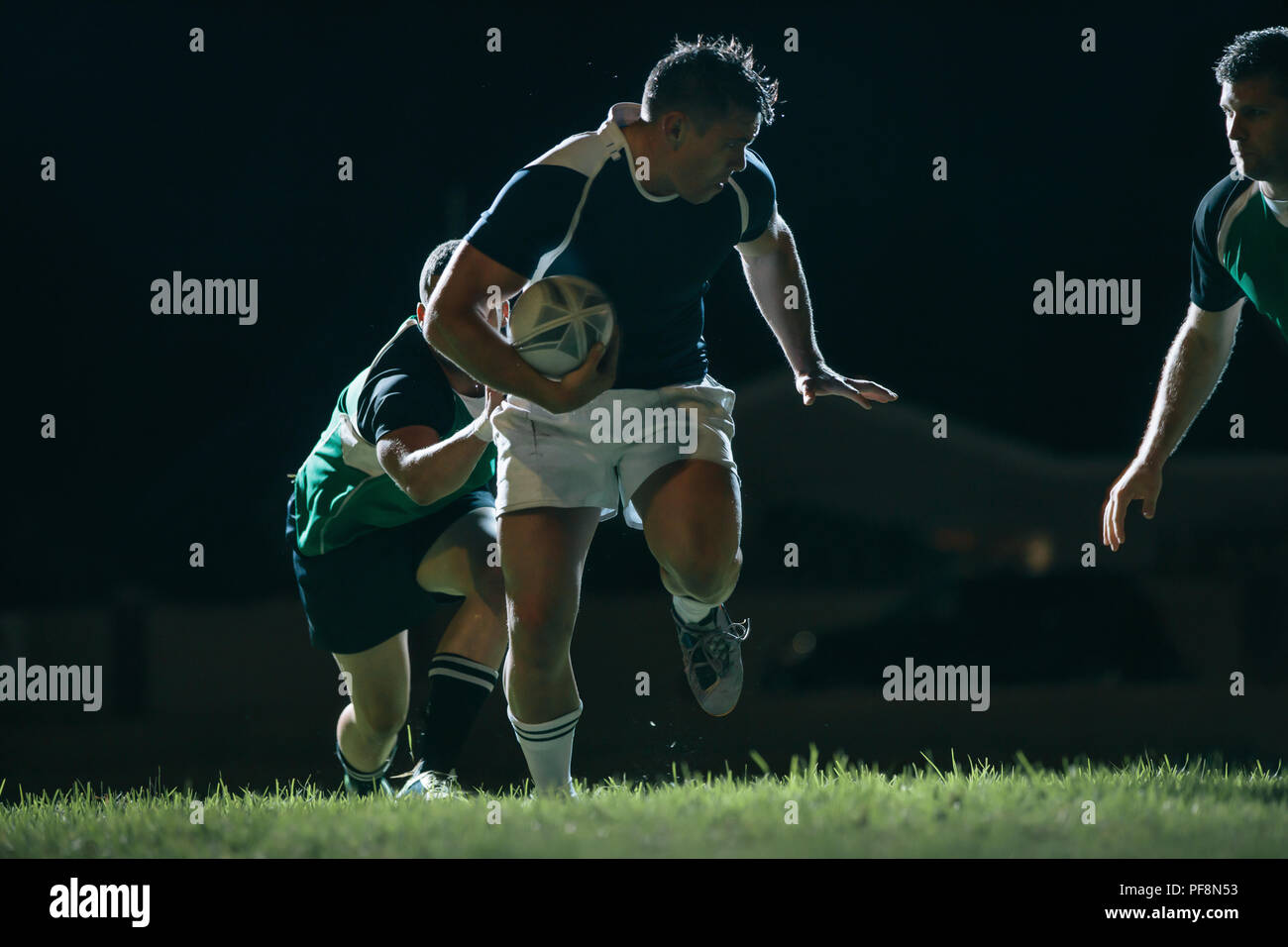 Flanker running with ball and tackling opponents during game. Rugby match in action. Stock Photo