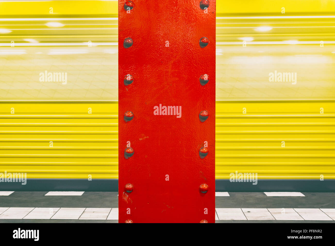 Berlin, Germany, July 21, 2018: Red Iron Column at Subway Platform Vinetastrasse with Moving Train in Background Stock Photo