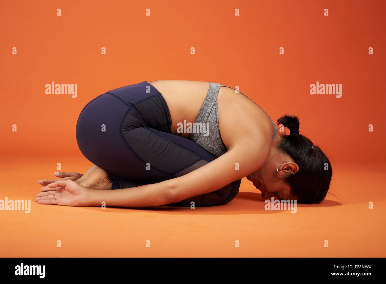 Child yoga asana pose. Woman in child yoga pose on studio background Stock Photo