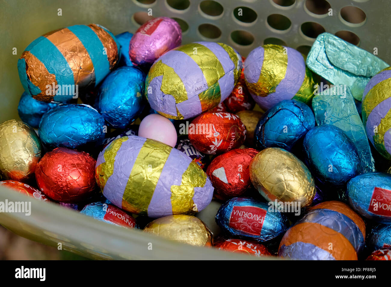 Closeup of chocolate Easter eggs wrapped in colourful foil from various stores in a basket