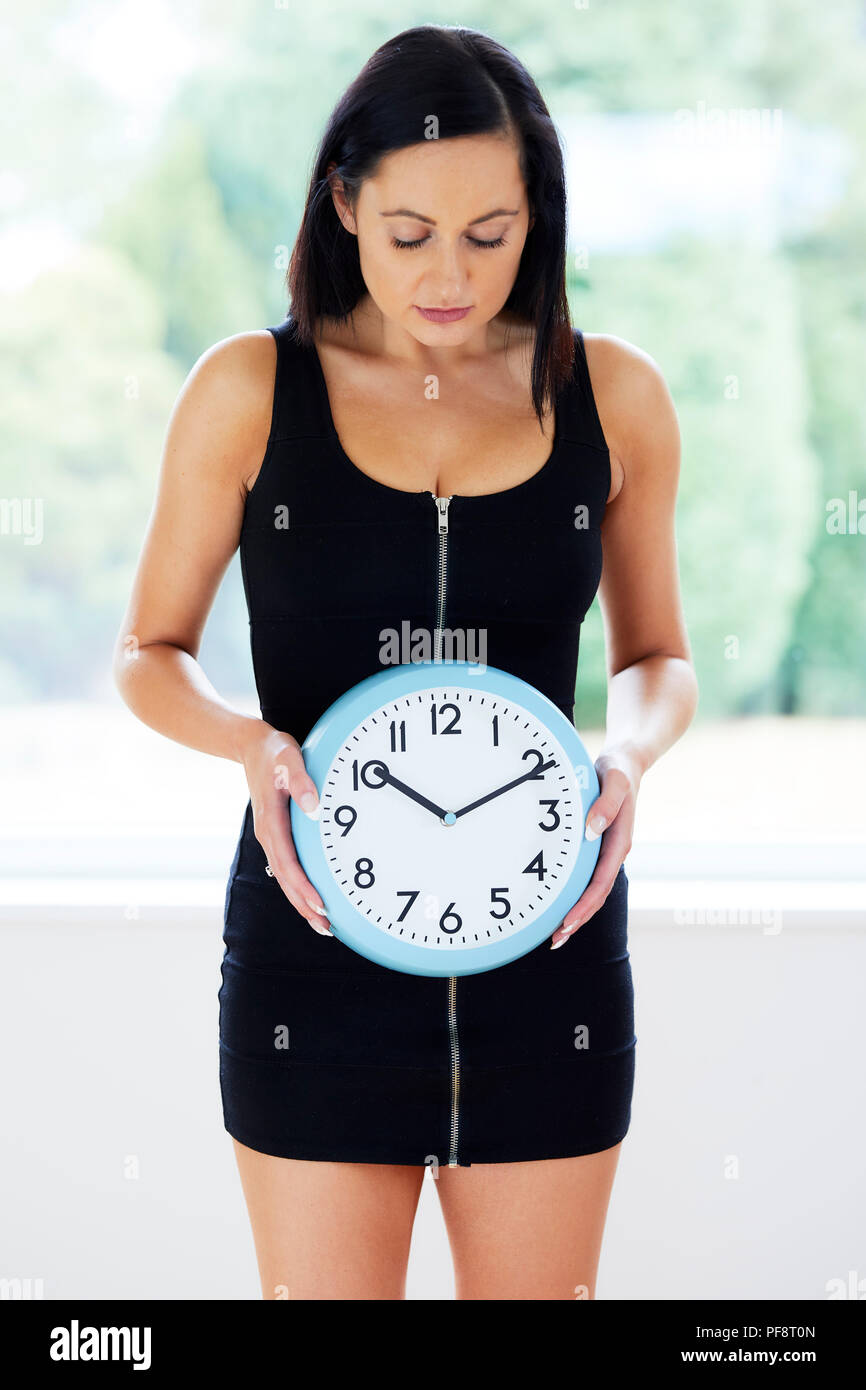 Woman stood holding a clock Stock Photo