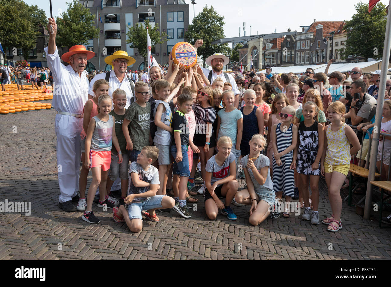 Alkmaar, Netherlands - July 20, 2018: Group of cheese carriers posing with a class of school children on the cheese market Stock Photo