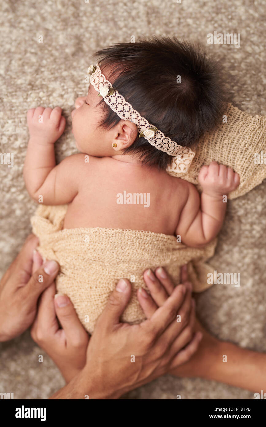 Taking care of newborn baby. Parents hands cover sleeping baby Stock Photo