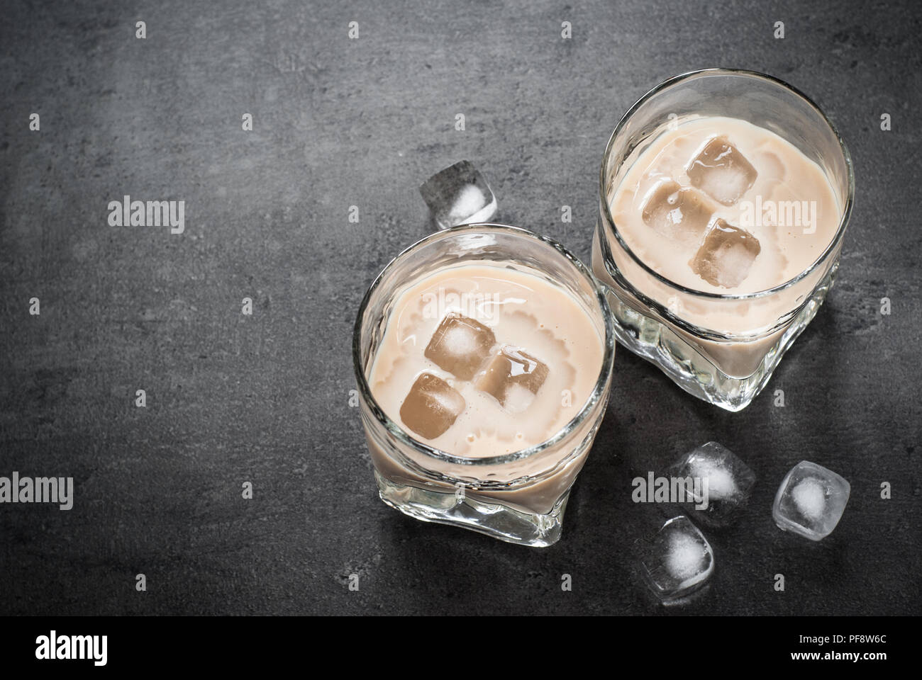 Irish cream liqueur in glasses with ice on black. Stock Photo