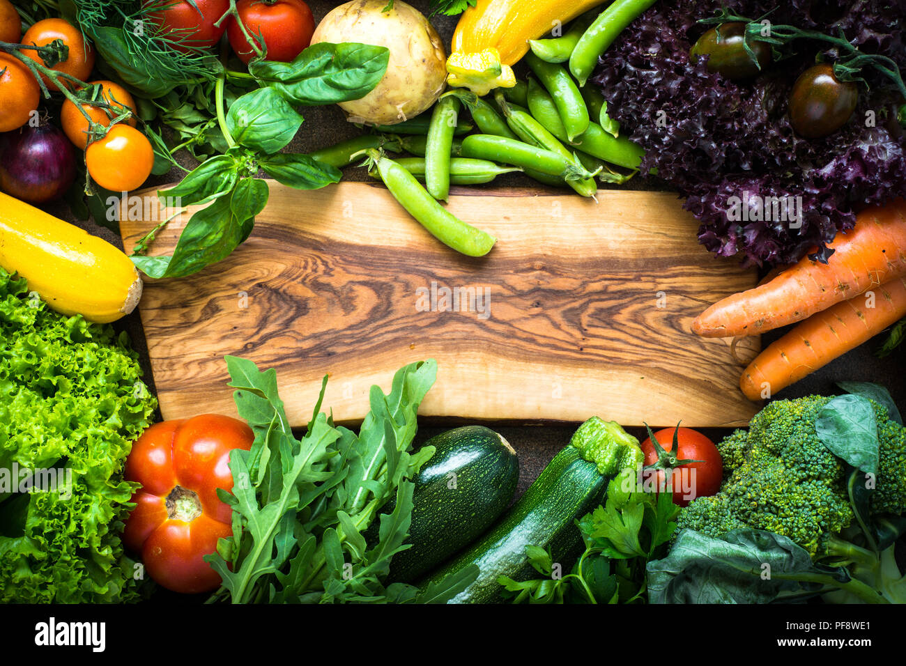 Frame of fresh vegetables around cutting board. Healthy food background