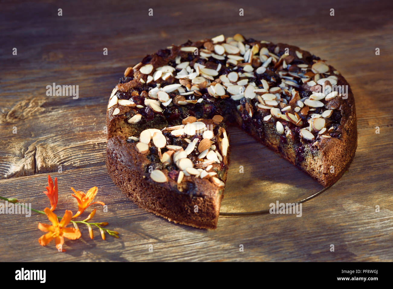 Healthy home-made Banana bread, sugar-free with almond flour, berries and almonds on a table, artistic country style food still life on rustic wooden  Stock Photo