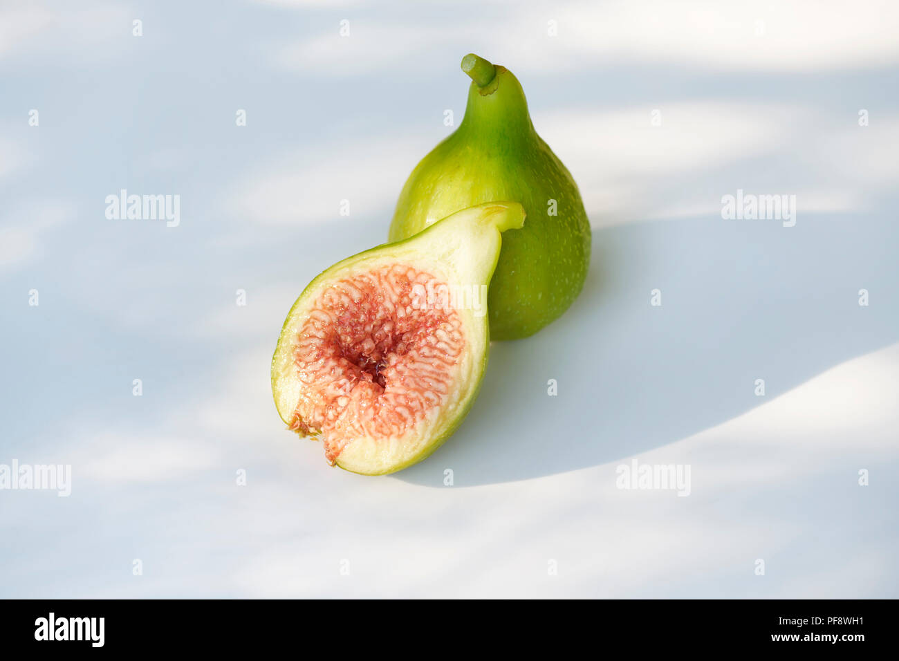 Freshly picked, ripe, organic Kadota figs with pink red pulp, artistic food still life isolated on white background Stock Photo