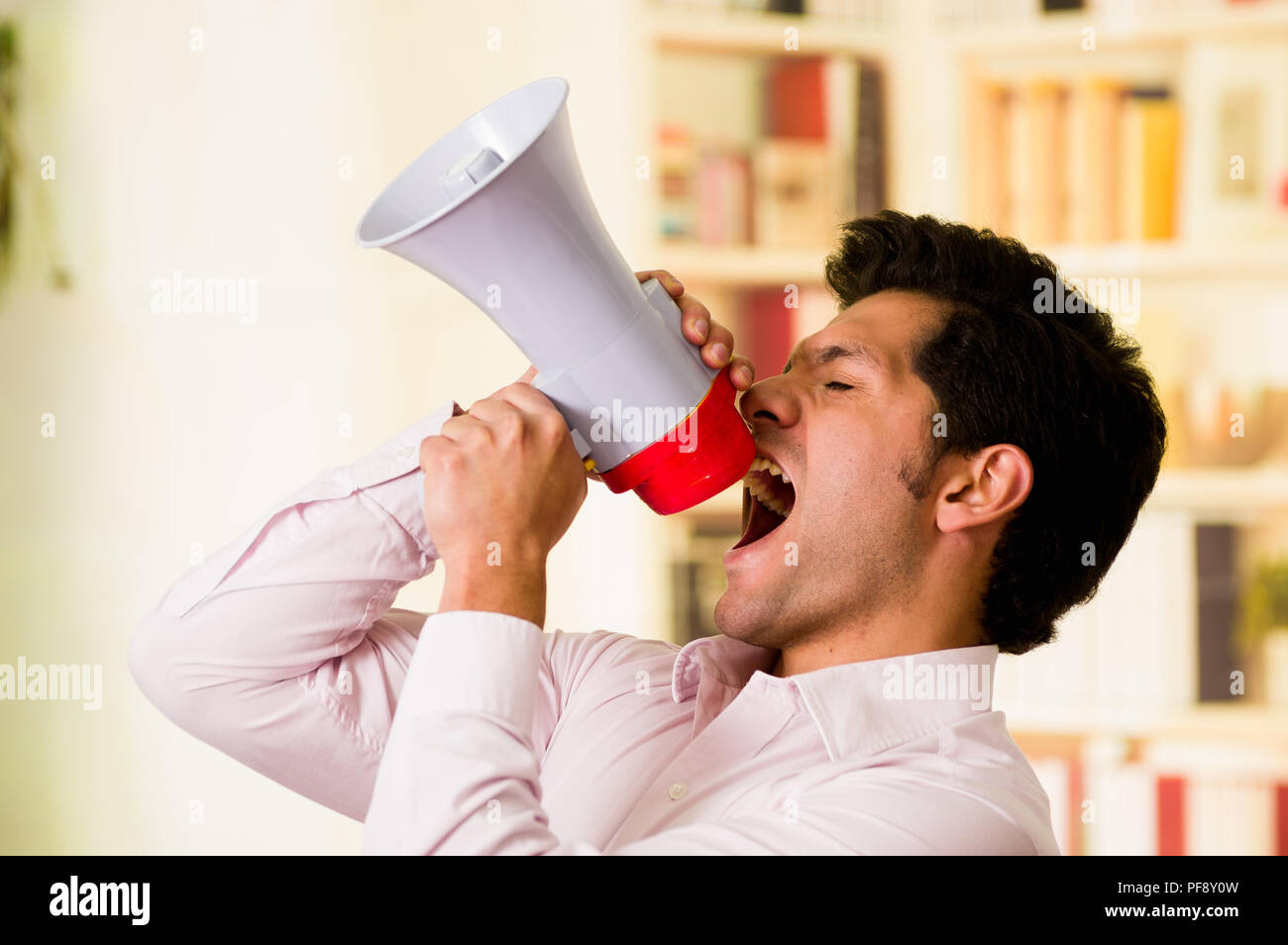 Portrait of a handsome man shouting with a megaphone while he is ...