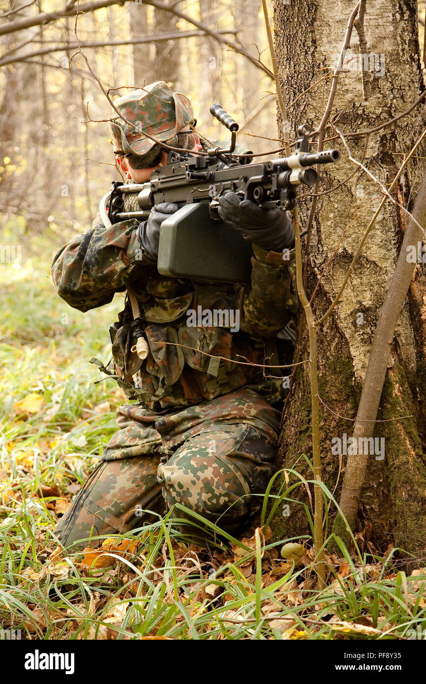 October 2009. Moscow Region, Russia - an airsoft player wearing german camouflage flecktarn aims at an enemy with m249 machin gun replica during a gam Stock Photo