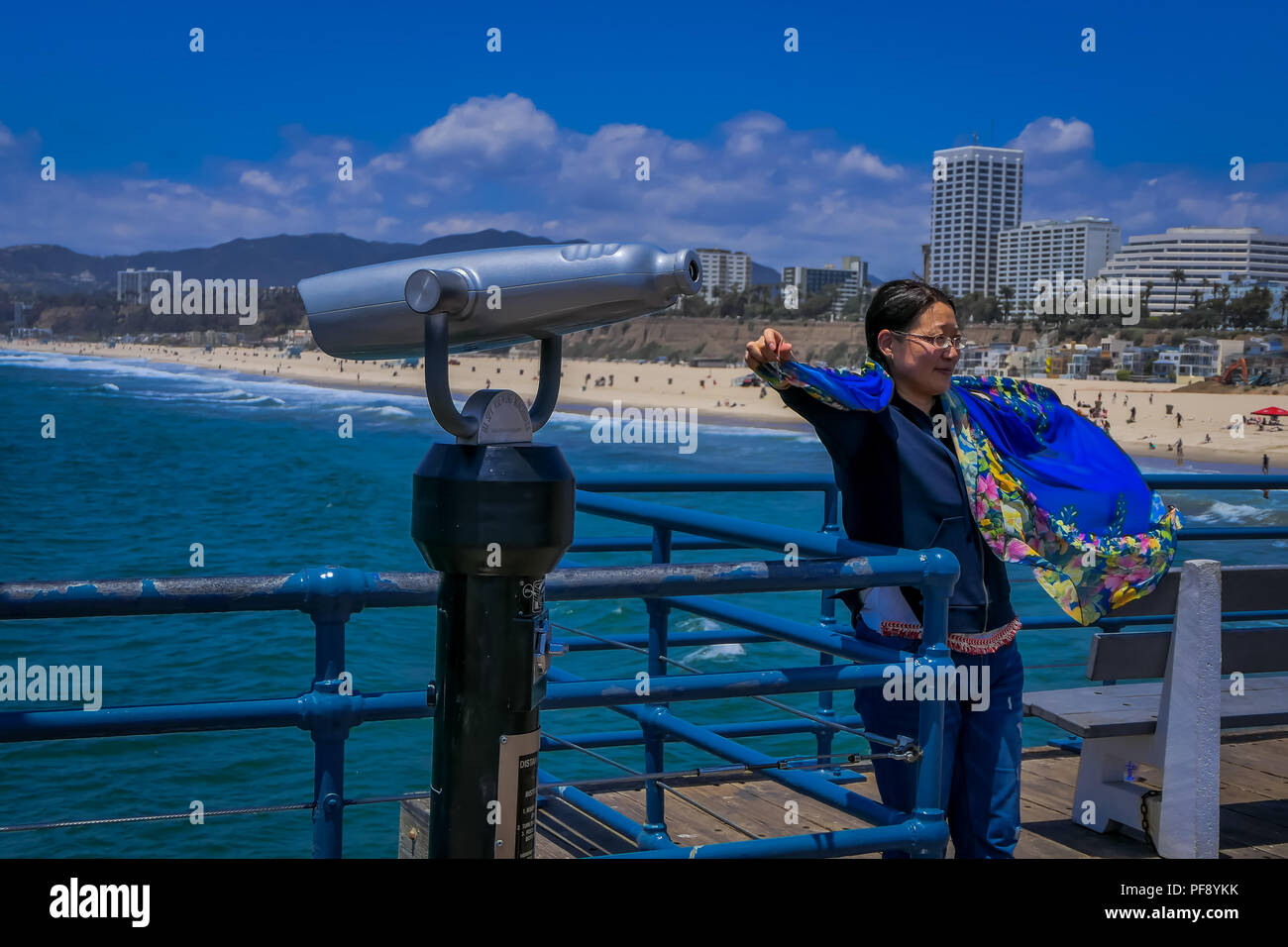 Los Angeles, California, USA, JUNE, 15, 2018: Cheerful female near coin operated optical binocular, enjoying sightseeing excited in Santa Monica pier in amusement park Stock Photo