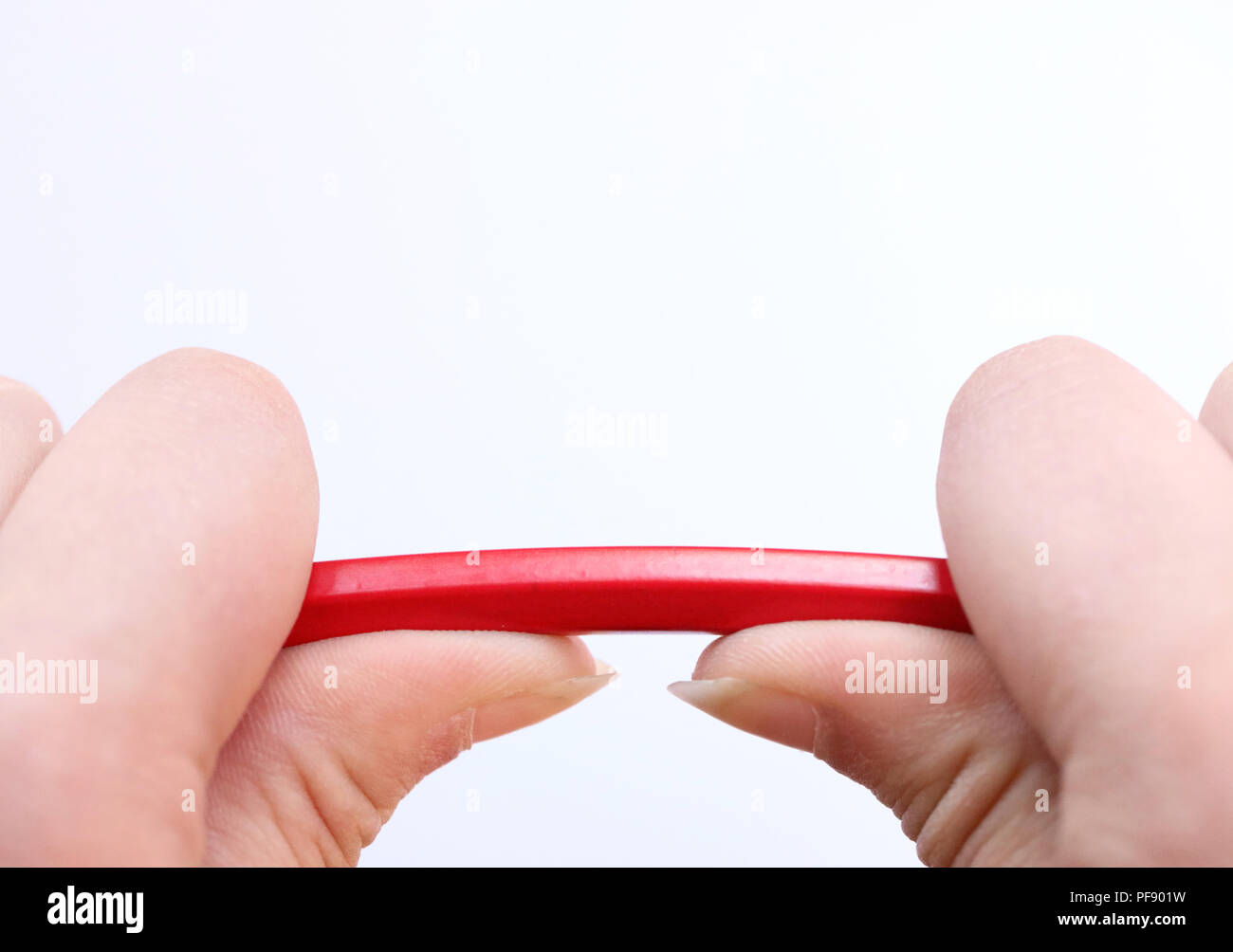 two hands holding a red pencil about to snap under the pressure. Concept of stress, anger management, pressure in the work place, parenting and breakd Stock Photo