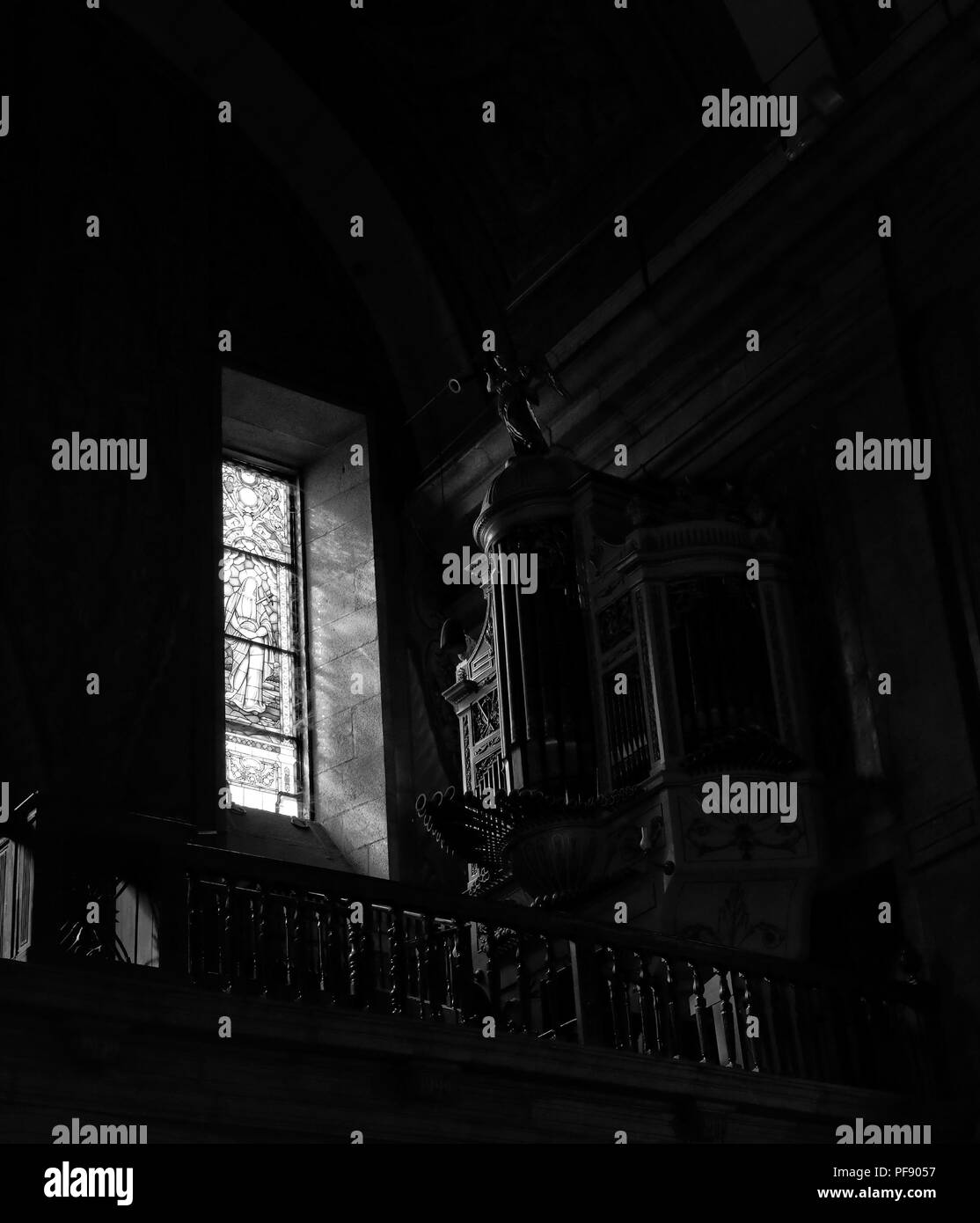 Old church organ illuminated by light filtered through a stained glass window. Converted black and white. High ISO photo. Stock Photo