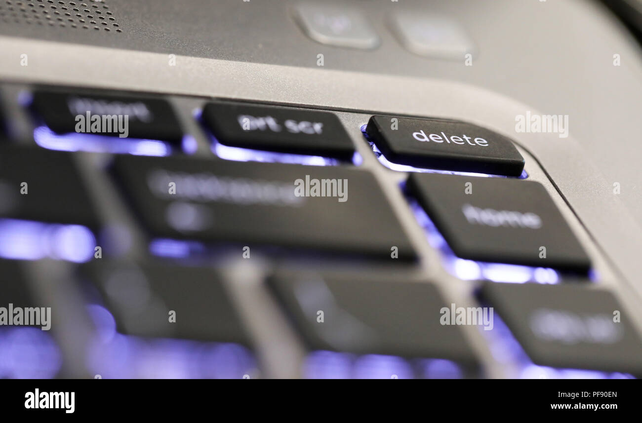 close up of  the delete symbol button tab on an illuminated laptop computer key board. The delete key Stock Photo