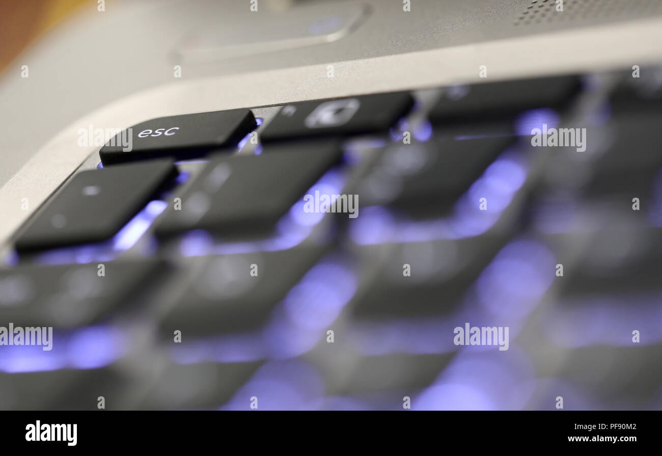 close up of the illuminated special key board character button escape. esc tab on a computer laptop keyboard. Stock Photo