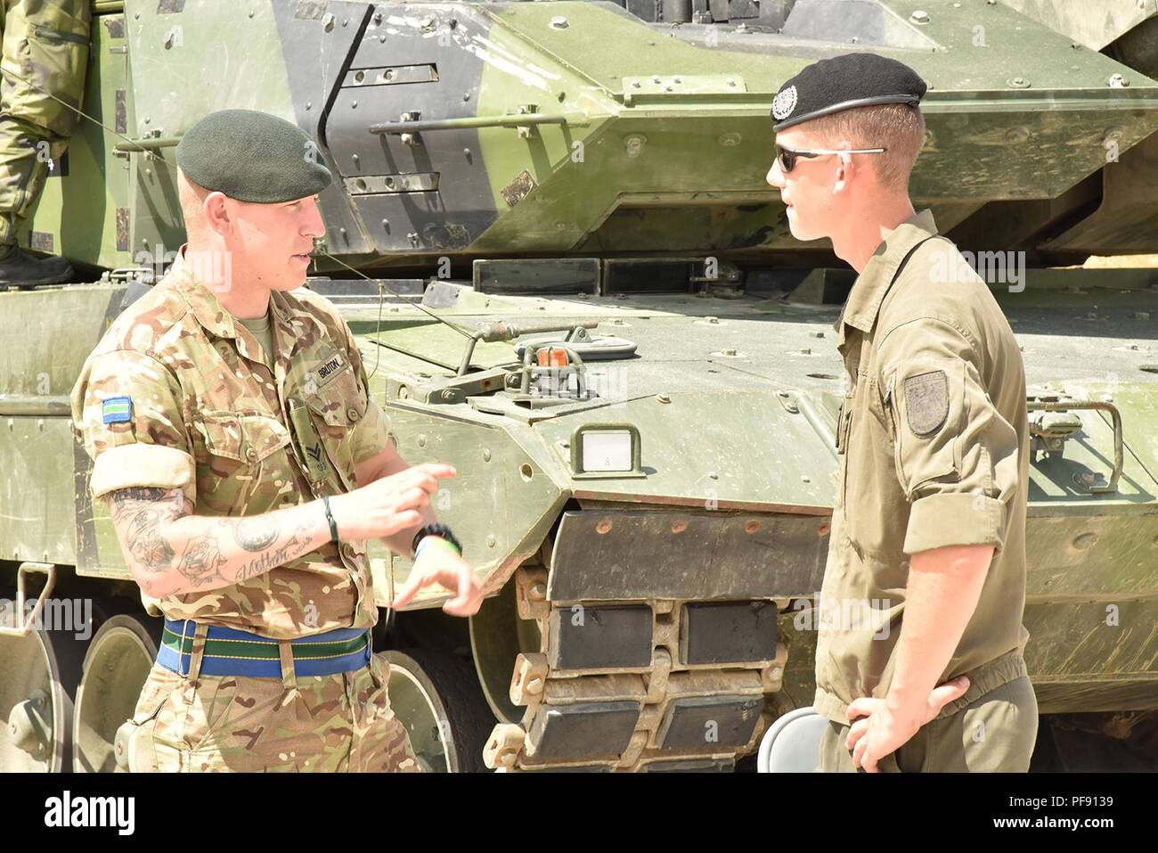 Tankers from the U.K.'s Queen’s Royal Hussars and Austria's 6th Tank Company, 14th Panzer Battalion talk before the opening ceremony of the Strong Europe Tank Challenge, held at 7th Army Training Command’s Grafenwoehr Training Area, June 3, 2018. U.S. Army Europe and the German Army co-host the third Strong Europe Tank Challenge at Grafenwoehr Training Area, June 3 – 8, 2018. The Strong Europe Tank Challenge is an annual training event designed to give participating nations a dynamic, productive and fun environment in which to foster military partnerships, form Soldier-level relationships, and Stock Photo