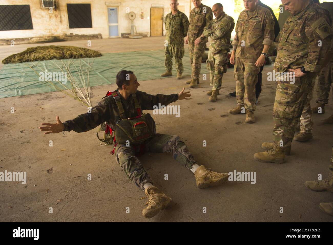 Marechal des Logis Chef Christophe, a jump master with the French Forces in Djibouti, demonstrates procedures to American parachutists at the 5th Arms Regiment Overseas base in Djibouti, June 3, 2018. Both countries trained together in preparation for the jump, parachuting in remembrance and honor of our nations’ friendship and alliance. Stock Photo