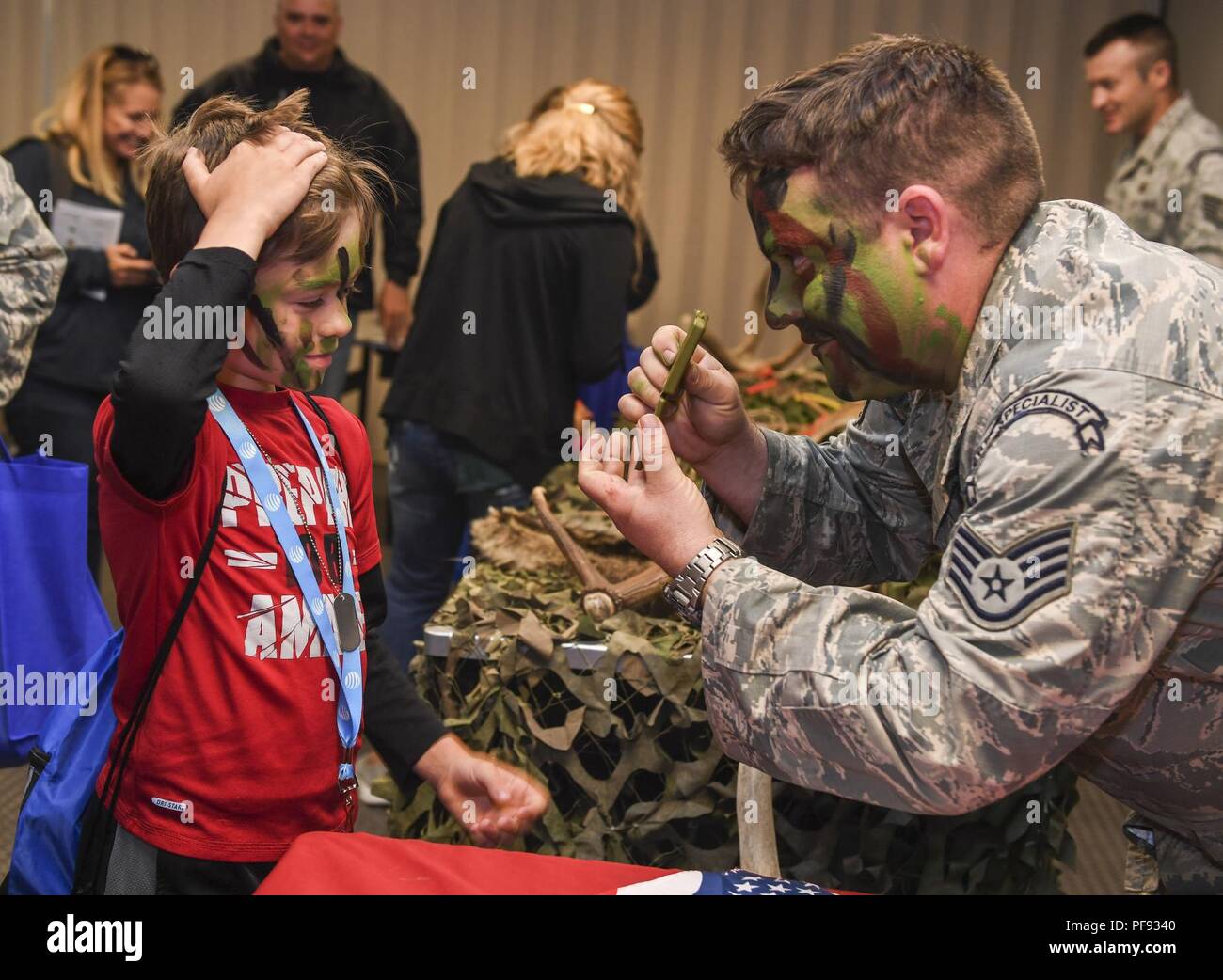 Staff Sgt. Anthony Barrette, 5th Operations Support Squadron survival,  evasion, resistance and escape specialist, shows a child his painted face  during Operation Heroes 2018 at Minot Air Force Base, North Dakota, June