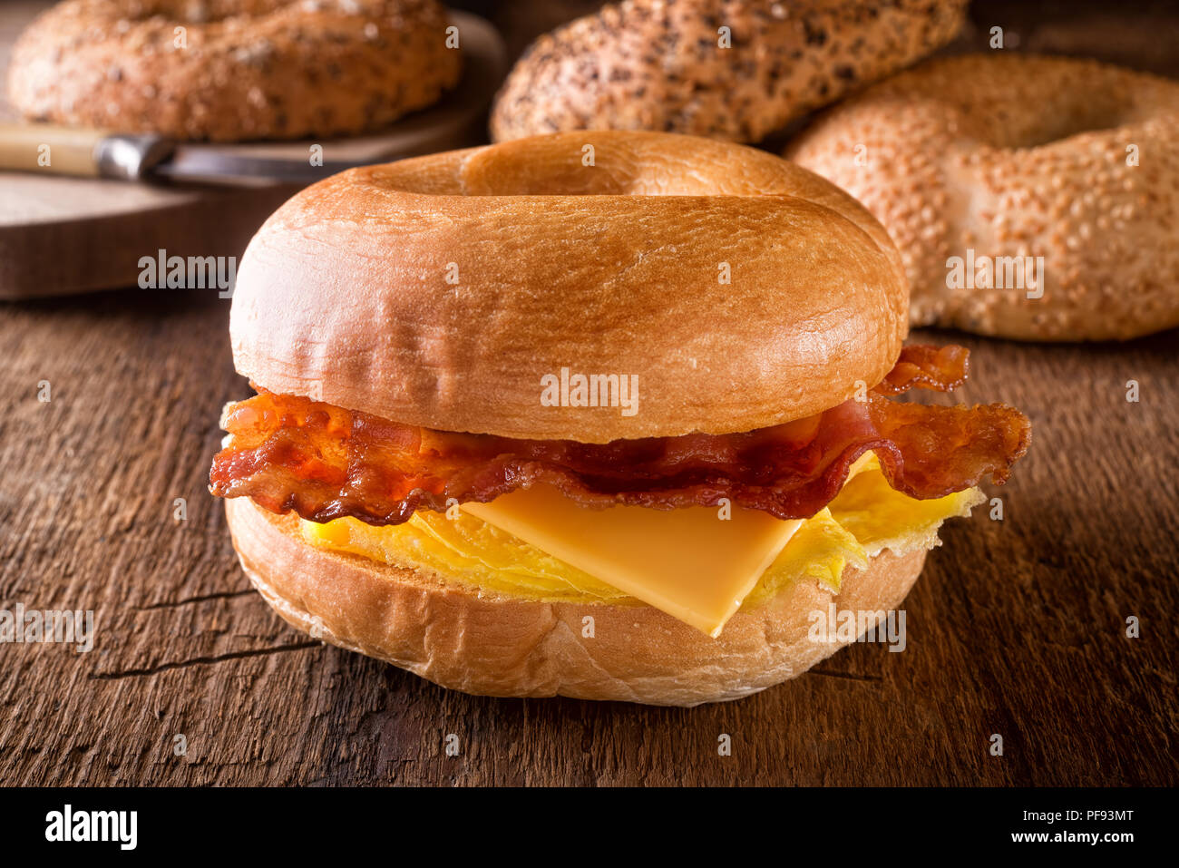 A delicious toasted breakfast bagel with egg, bacon and cheese. Stock Photo