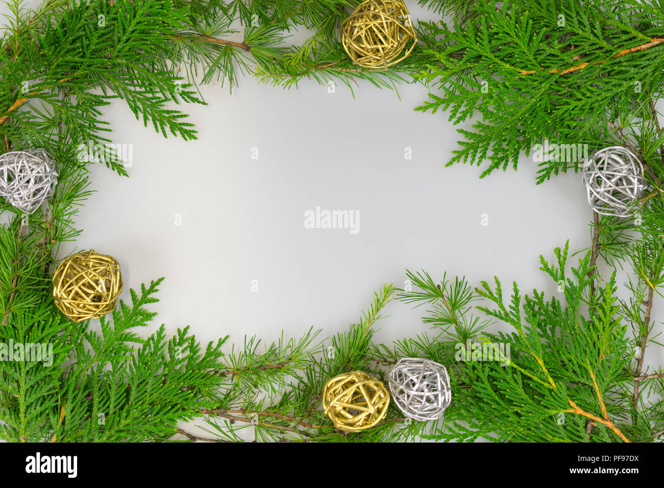 a border of cedar, white pine, and tamarack branches with silver and gold twig balls and copy space in the middle for your message Stock Photo