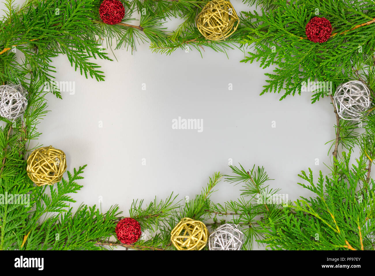 a border of cedar, white pine, and tamarack branches with silver and gold twig balls and red ornaments with copy space in the middle for your message Stock Photo
