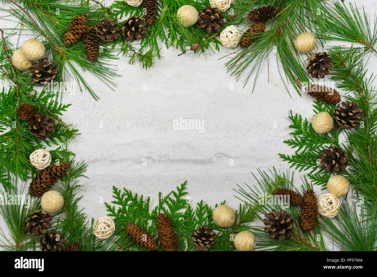 A beautiful border of white pine, tamarack and cedar boughs with pine cones, cinnamon sticks, and balls of twigs and twine Stock Photo