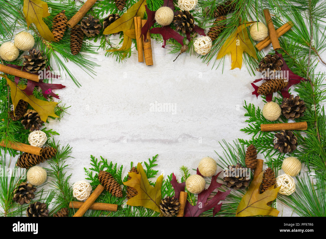 A border of cedar, white pine, and tamarack branches along with scotch pine. spruce, and hemlock pine cones, cinnamon sticks, and twine and twig  ball Stock Photo