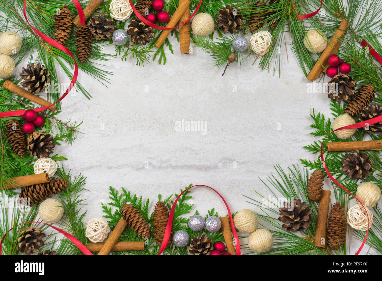 A border of cedar, white pine, and tamarack branches along with scotch pine. spruce, and hemlock pine cones, cinnamon sticks,twine and twig  balls, re Stock Photo