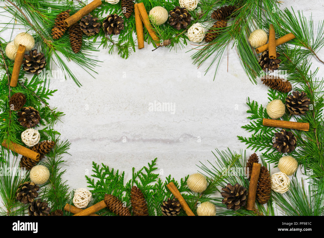 A beautiful border of white pine, larch,and cedar boughs with pine cones, cinnamon sticks, and balls of twigs and twine Stock Photo