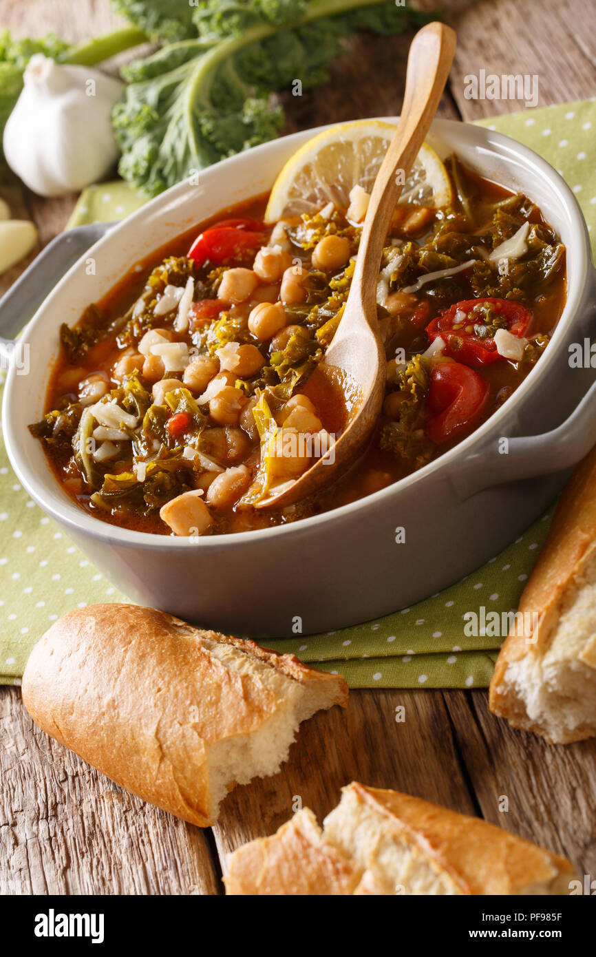 Vegetable soup of chickpeas, kale, tomatoes, garlic and potatoes close up in a bowl on the table. vertical Stock Photo