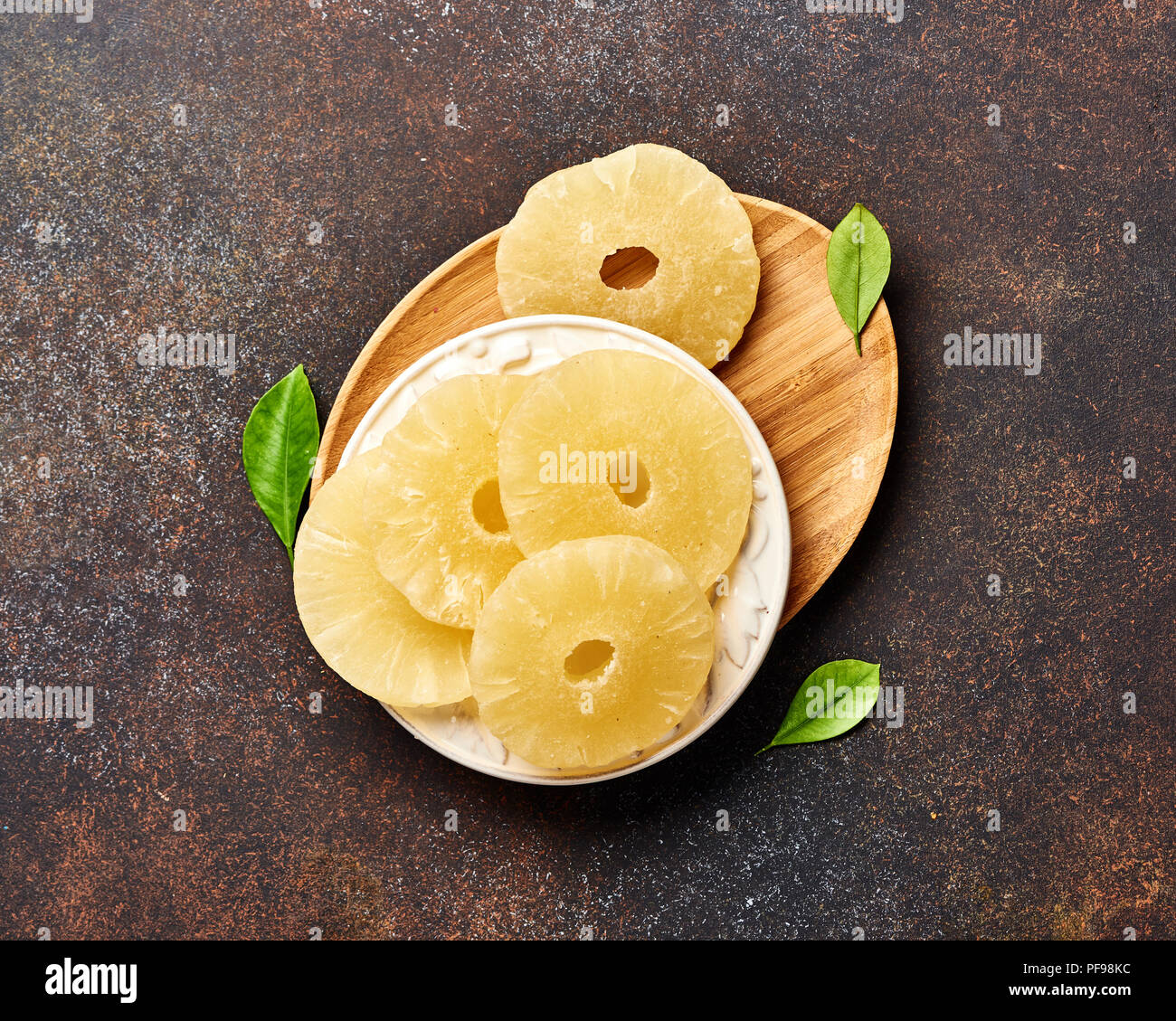 Dried pineapple rings on a brown table. Top viw of sweet paneapple slices. Stock Photo