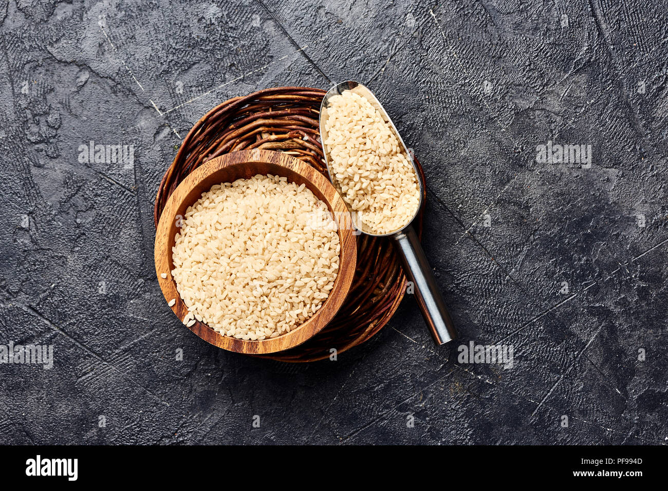 White rice in wooden bowl on black background. Top view of grains. Stock Photo