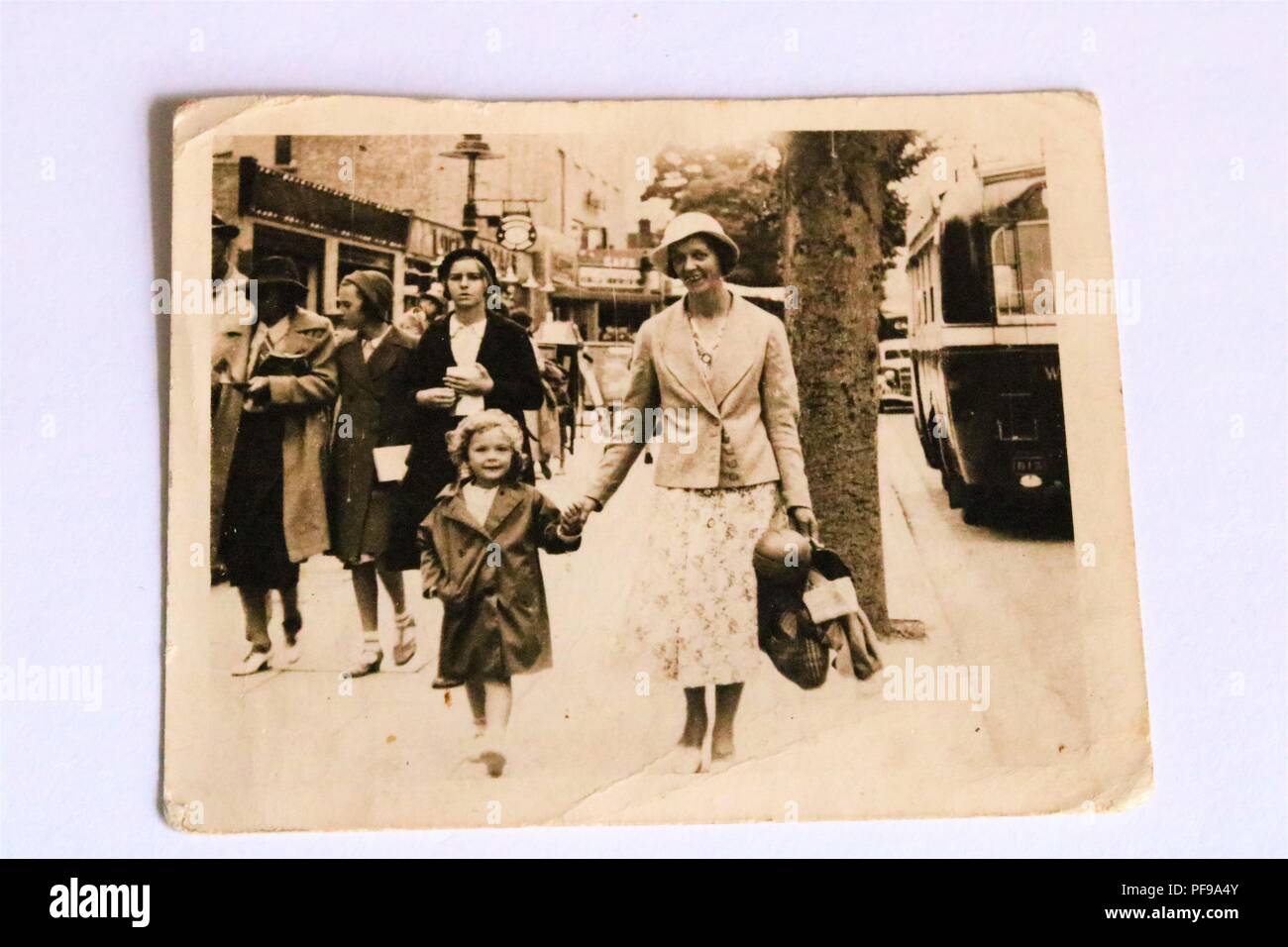 Social History - Black and white old photograph showing an elegant lady wearing a hat and holding hand of child walking in the street - 1930s Stock Photo
