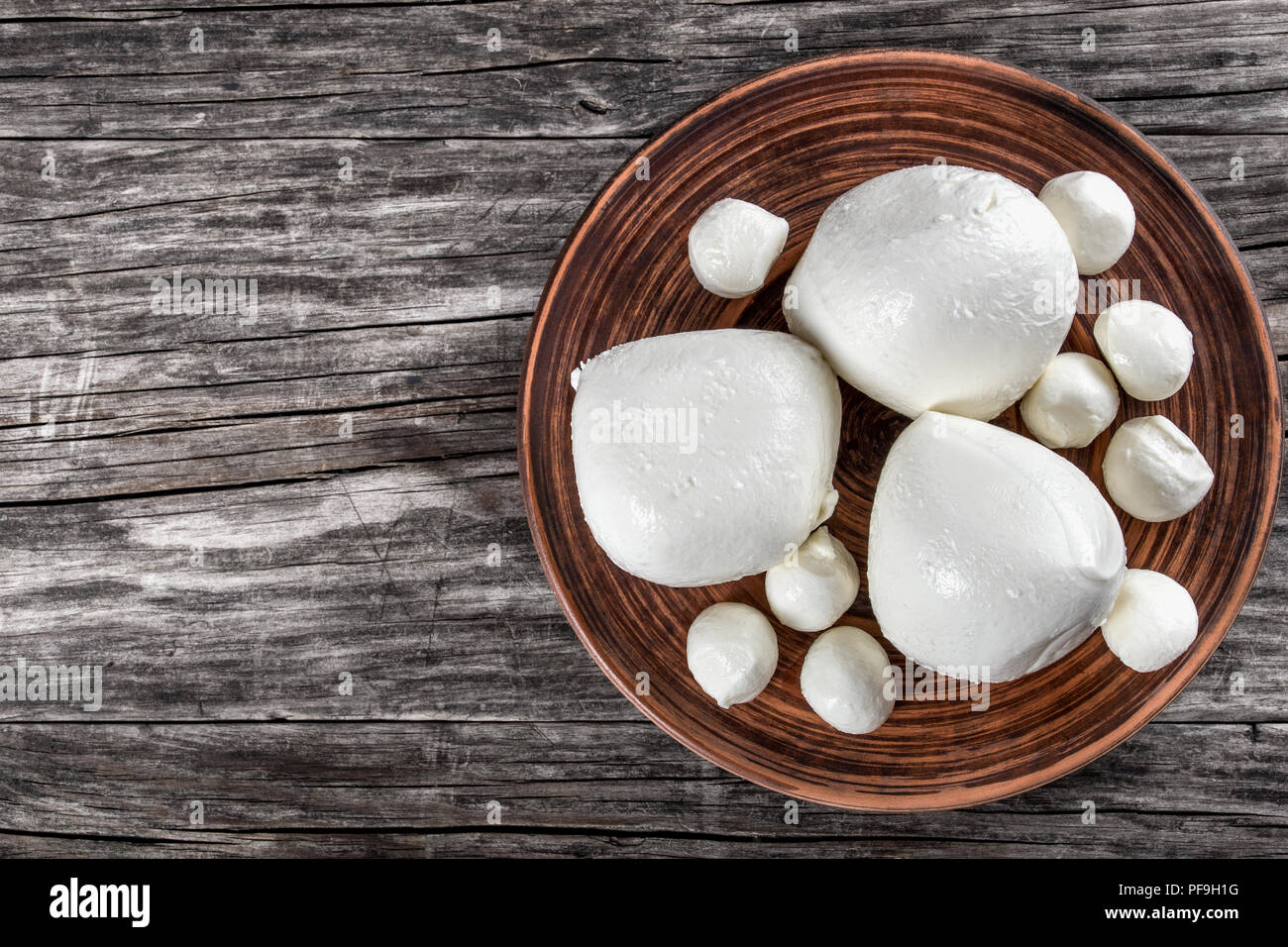 mozzarella balls on a clay dish on an old rustic table, top view Stock Photo