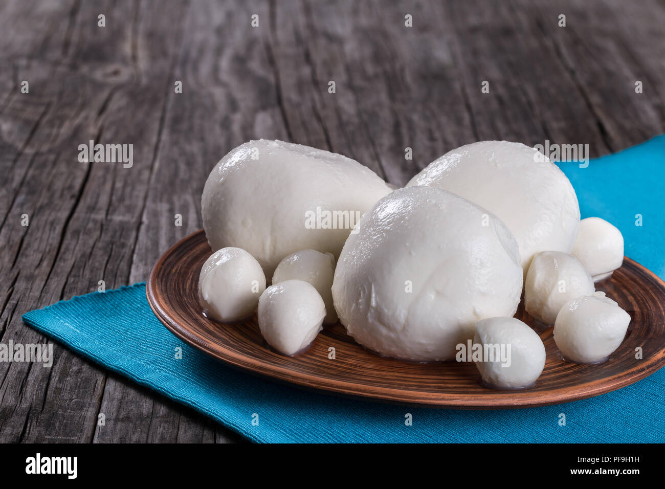 mozzarella balls on a clay dish on an old rustic table on a table napkin,  close-up Stock Photo