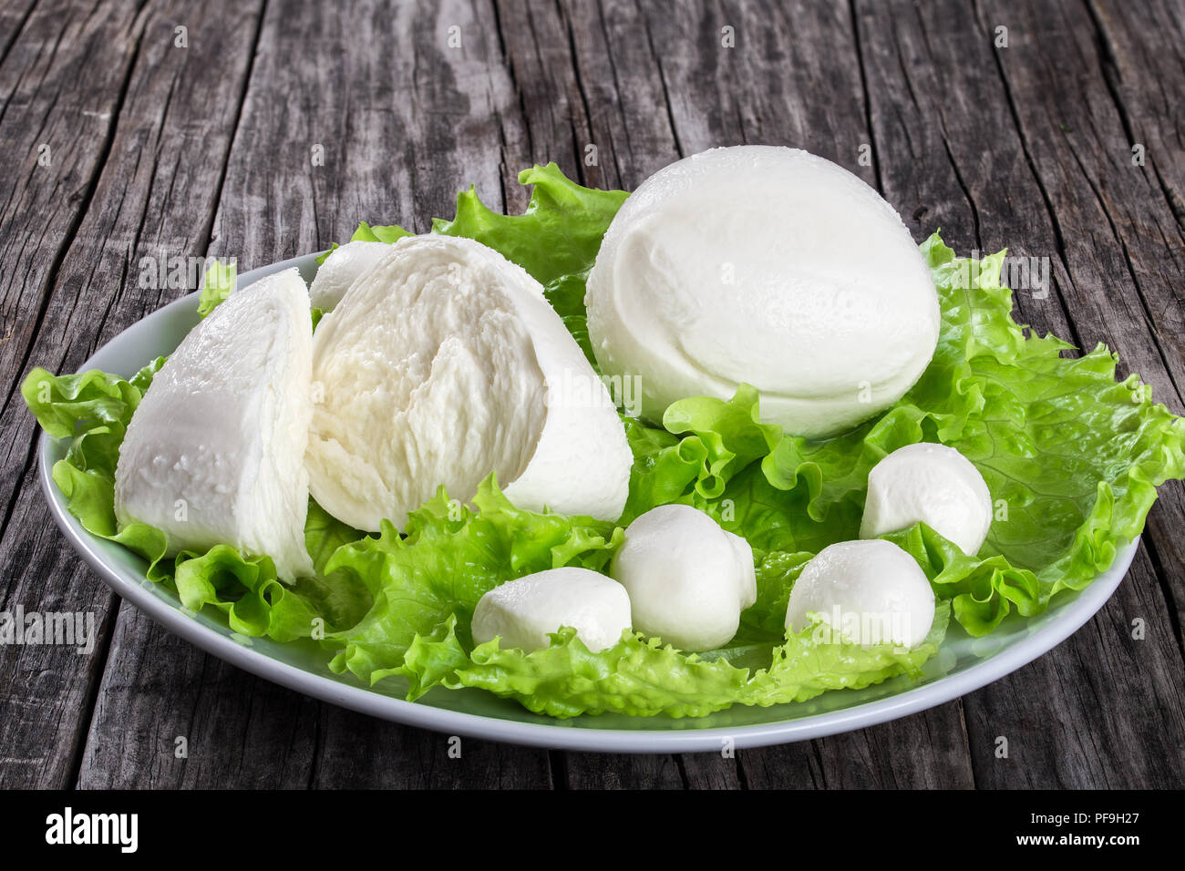 mozzarella balls and lettuce leaves on a dish on an old rustic table,  close-up Stock Photo