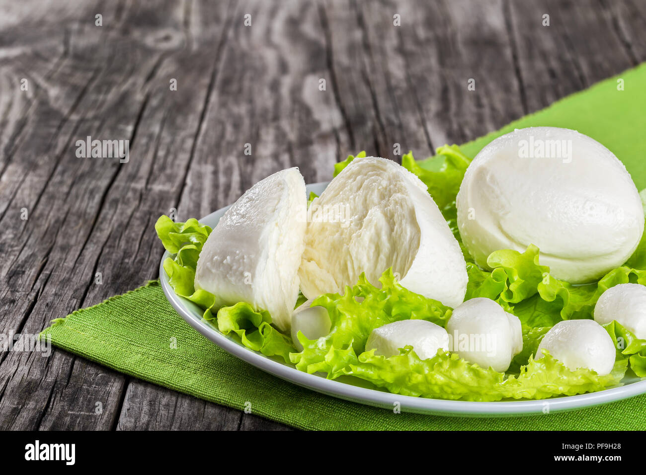 mozzarella balls on a white dish on an old rustic table on a table napkin,  close-up Stock Photo
