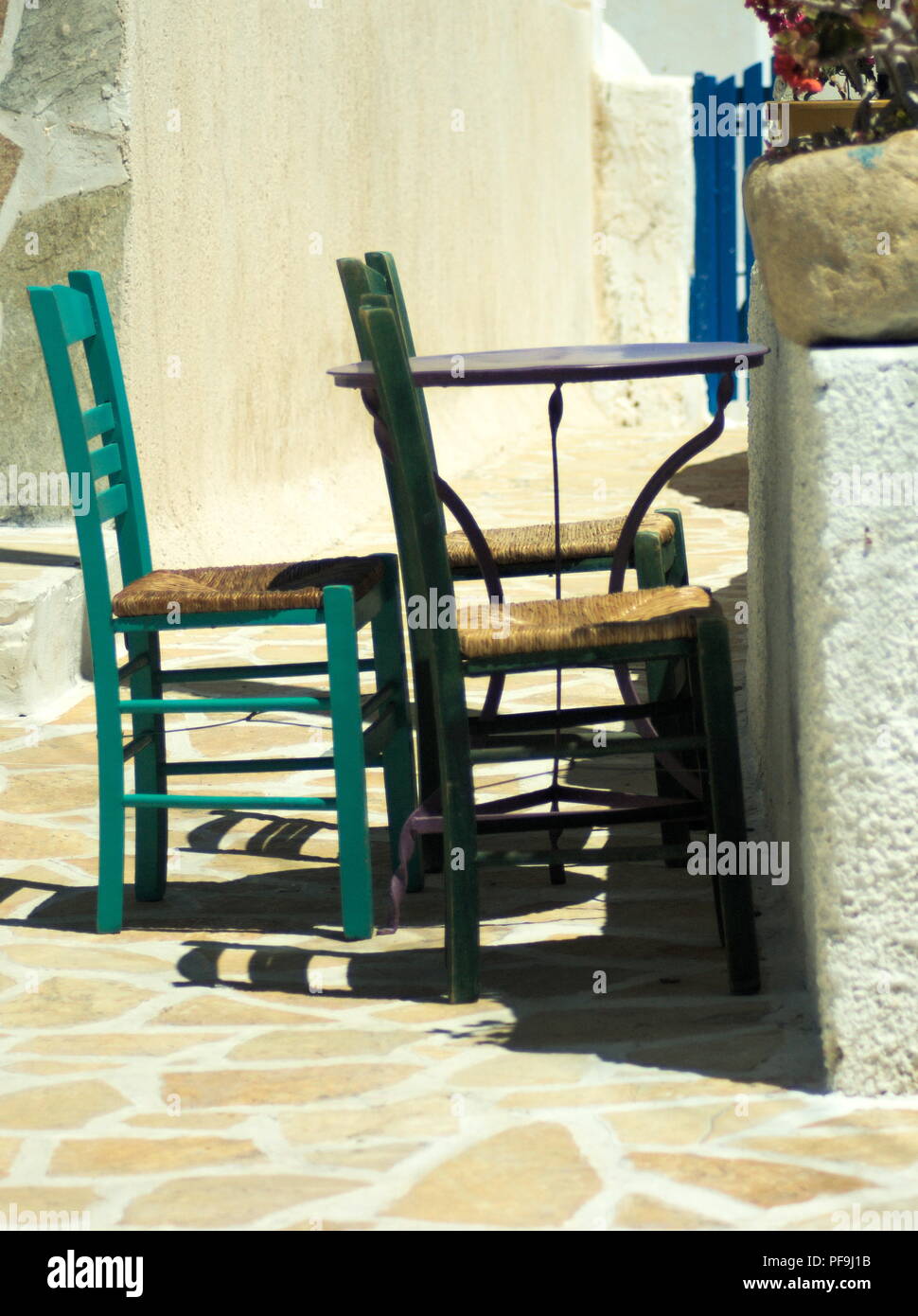 The quiet and remote island of Anafi in Greece. A simple scene, a traditional table and three chairs.  The beauty is in the simplicity Stock Photo