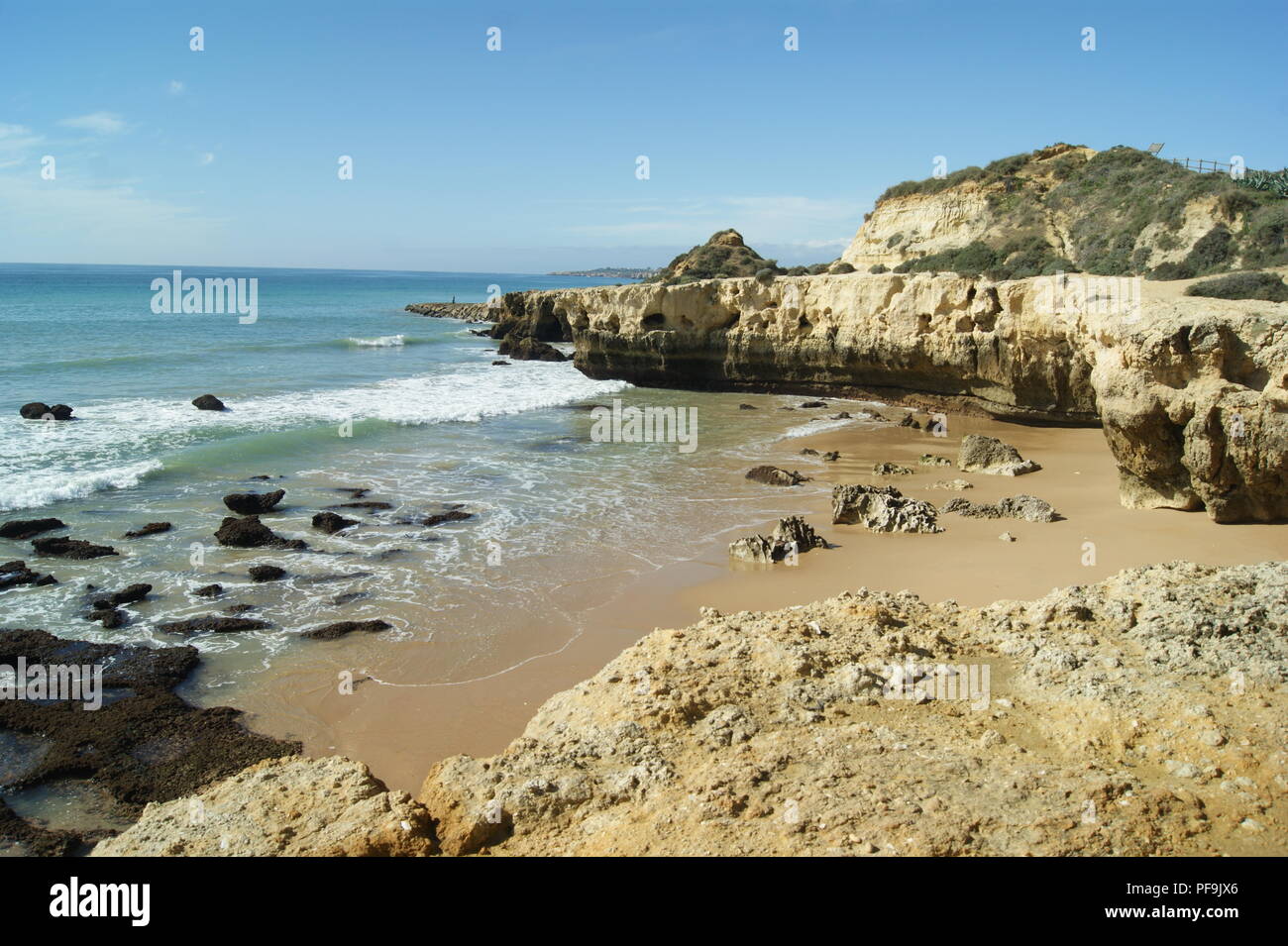 A quiet cove at the Portuguese resort of Albufeira. Atlantic waves break on to a deserted sea shore.  A winters day, with bright sunshine. Stock Photo