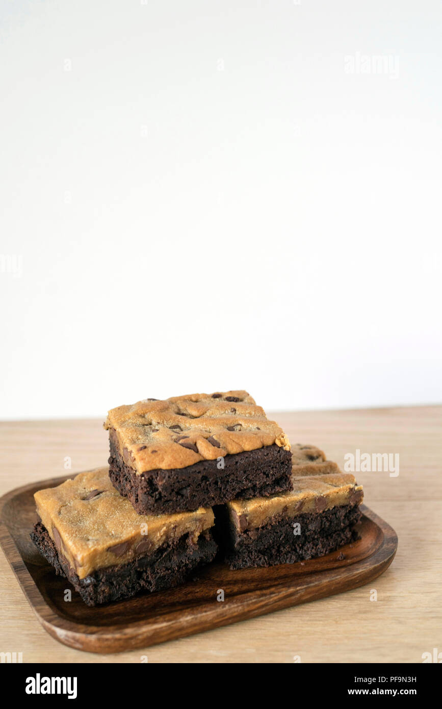 Rich Brookie Bars Stacked on a Wooden Plate in front of a Light Background Stock Photo