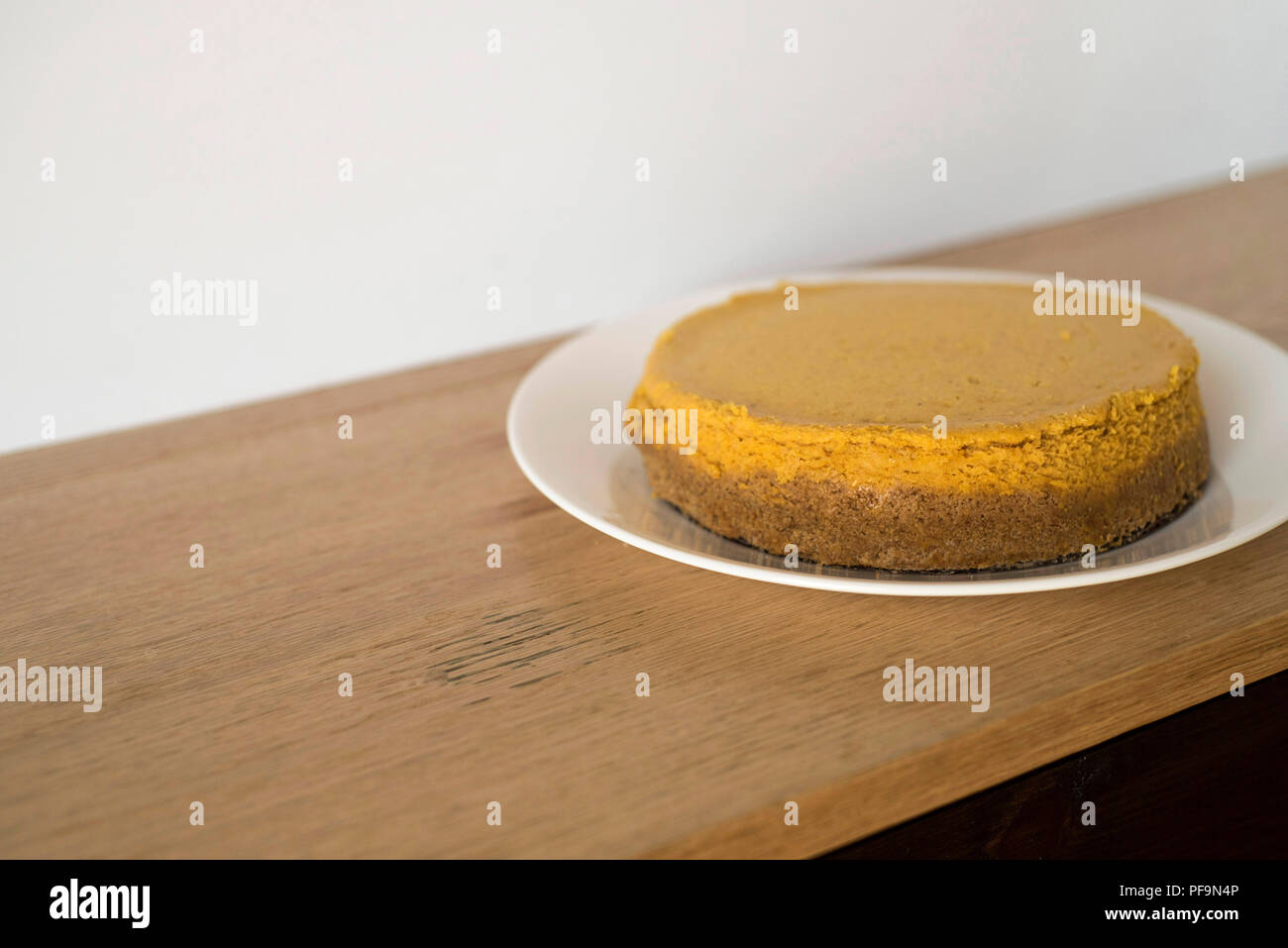 Whole Pumpkin Cheesecake Waiting on a Wooden Counter to Be Eatn Stock Photo