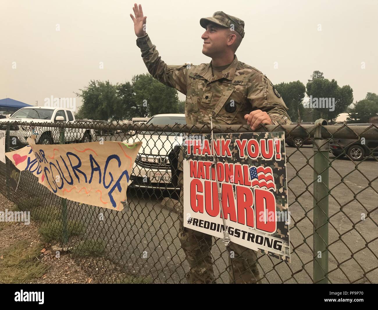 California Army National Guard's Spc Justin C Piers of the 870th Military Police Company, 185th Military Police Battalion, 49th Military Police Brigade, responds to residents shouting 'Thank You' as they pass the incident command post July 30 in Anderson, California, where the Cal Guard operates for the Carr Fire, July 31, 2018. Image courtesy Staff Sgt. Edward Siguenza/California National Guard. () Stock Photo
