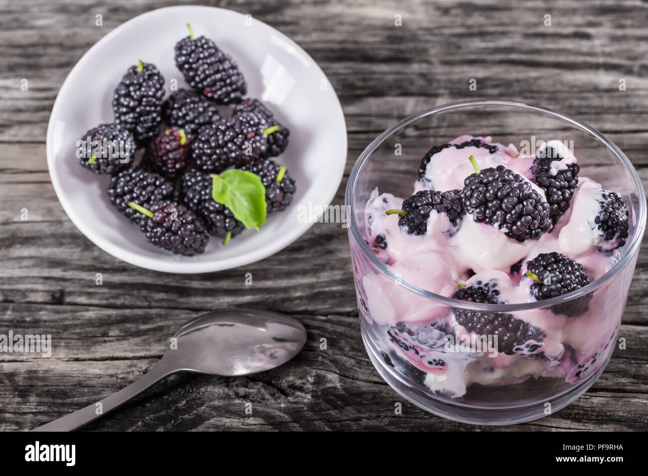 fresh greek colored stains yogurt with berries in glass cup on table with spoon, view from above