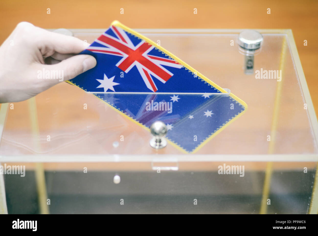 Man inserting Flag of Australia into ballot box, voting and elections in Australia Stock Photo