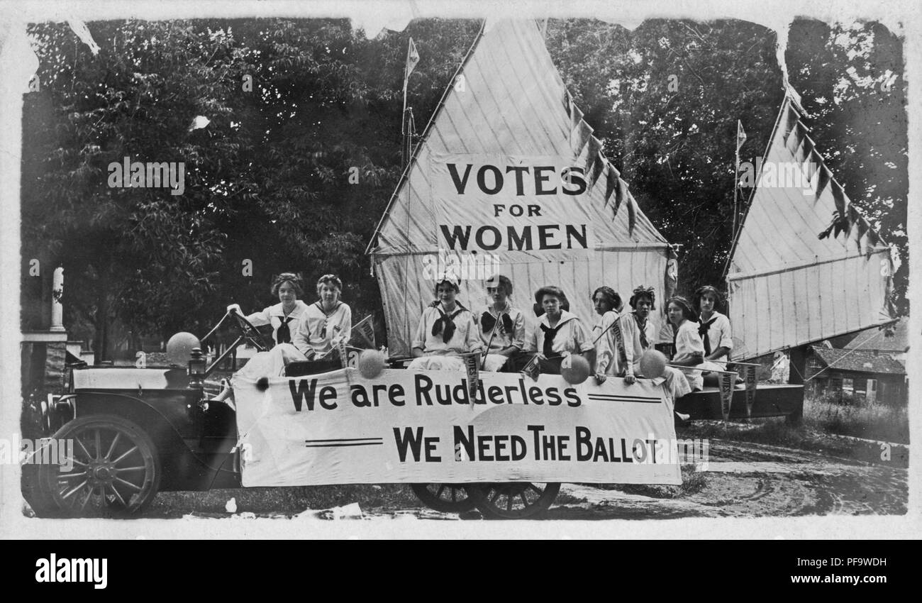 Black and white photograph showing a group of young female suffragists, wearing sailor costumes, seated on a float decorated to resemble a boat, the mainsail reads 'Votes for Women, ' and the marquee reads 'We Are Rudderless - We Need The Ballot', 1900. () Stock Photo