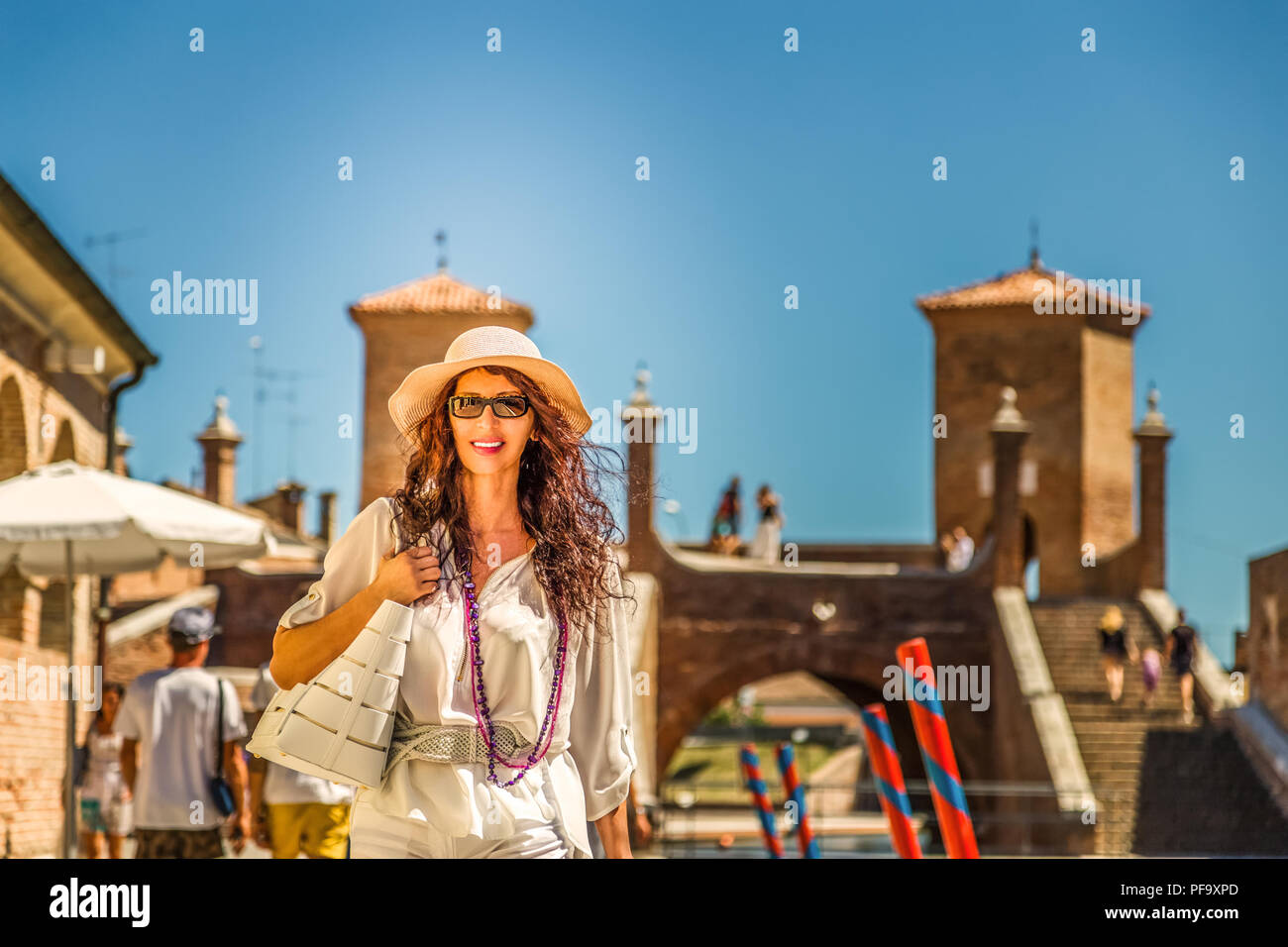 Mature woman with wide hat on vacation goimg for shopping in a Venice-like town in Italy Stock Photo
