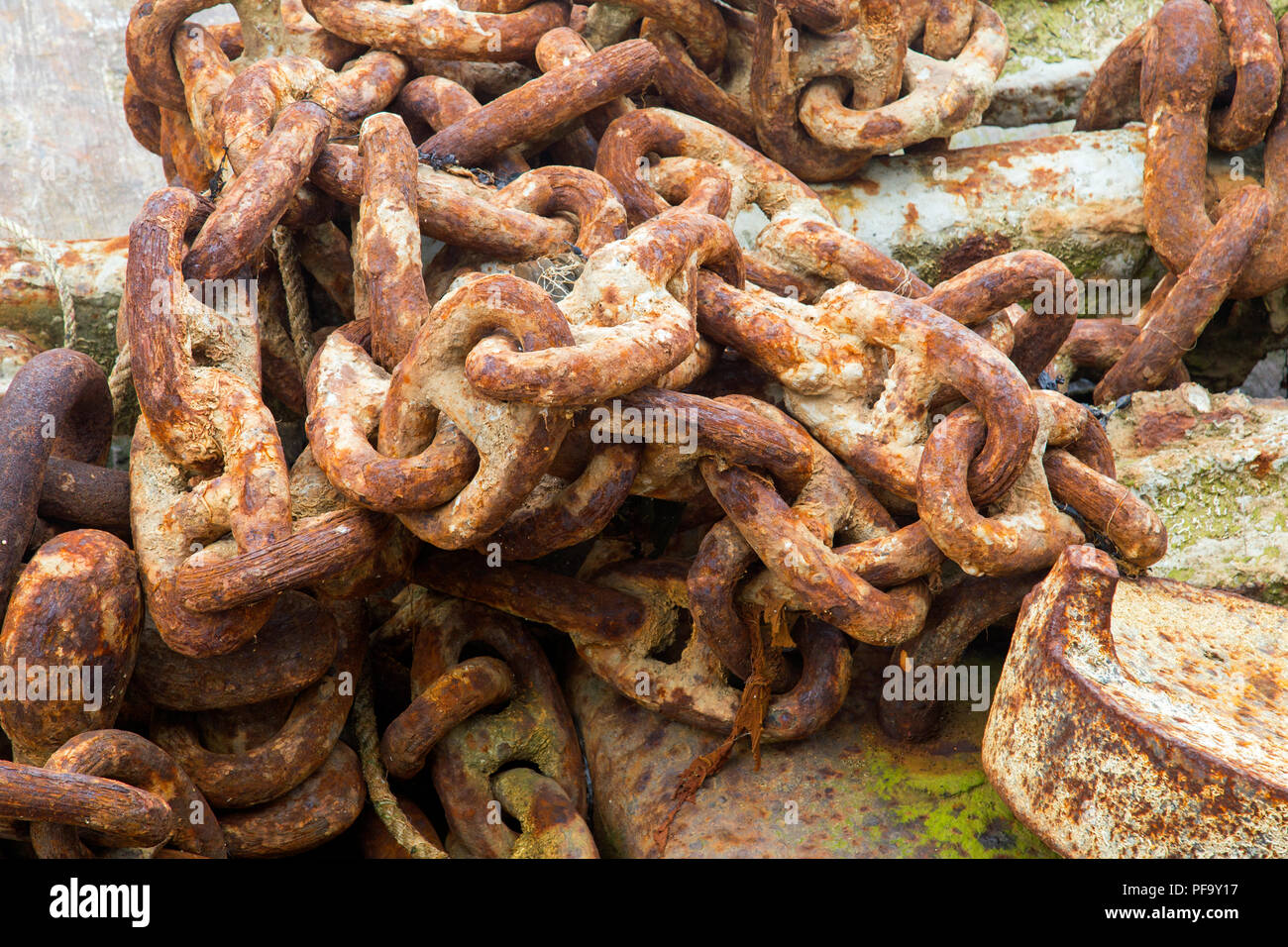 Rusty iron chains in a heap on rocks shot from above Stock Photo