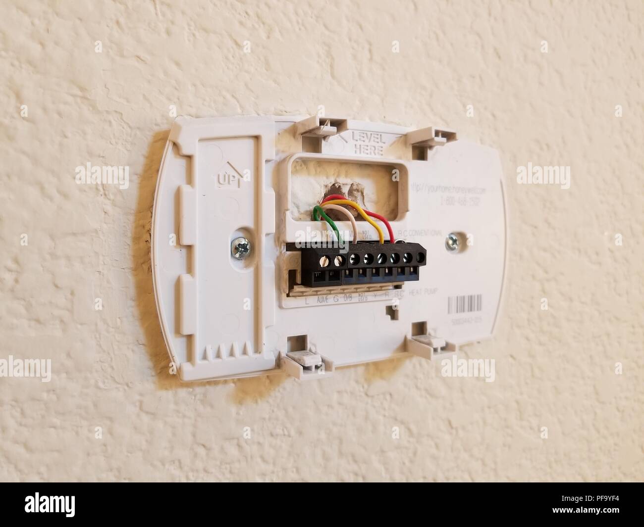 Installation of a programmable thermostat, showing low-voltage wires inserted into thermostat back plate, in a suburban home, San Ramon, California, May 4, ...